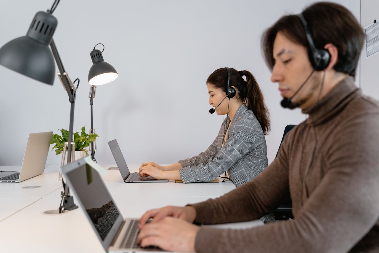services-02 Business professionals working in a call center, wearing headsets and using laptops.